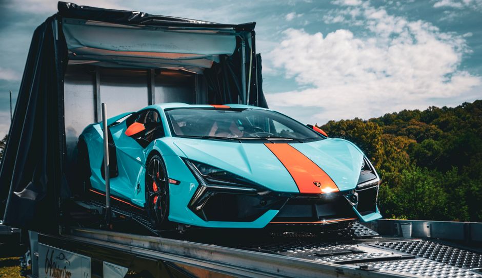 An exotic sports car being loaded into an enclosed transport trailer